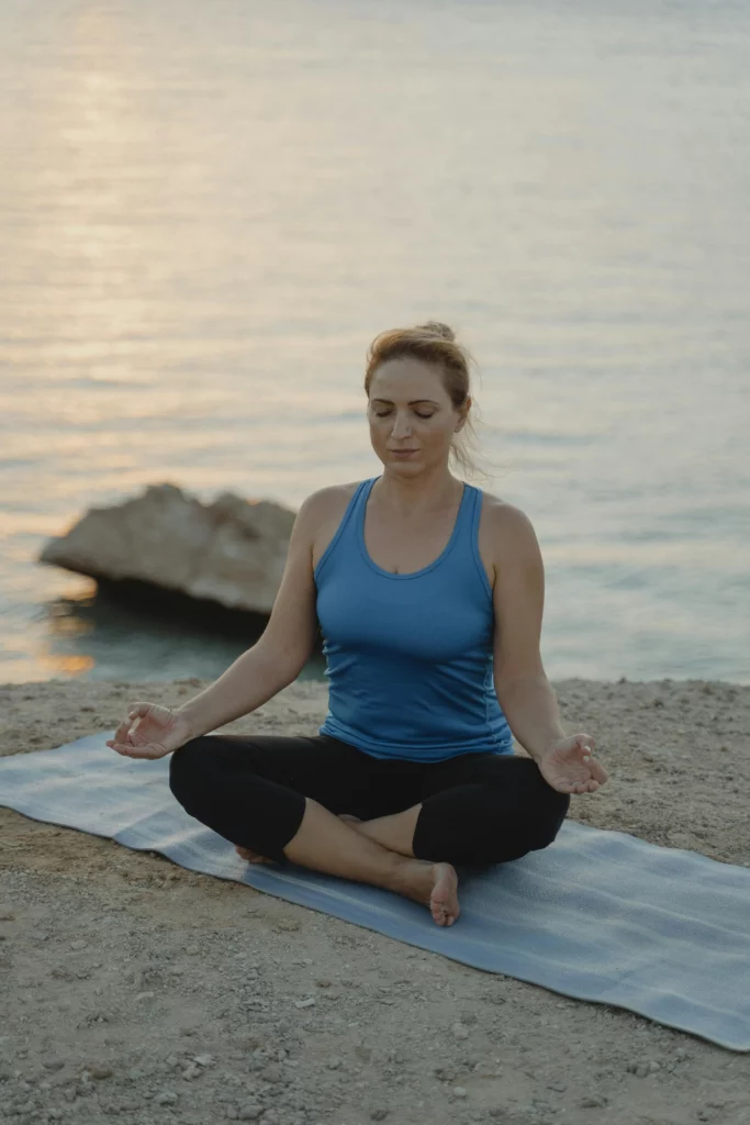 A lady doing yoga and mindfulness by the beach. A confidence exercise