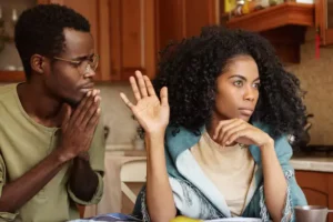 Man asking for forgiveness from his wife after infidelity. Wife waving hand to show she's not interested in listening