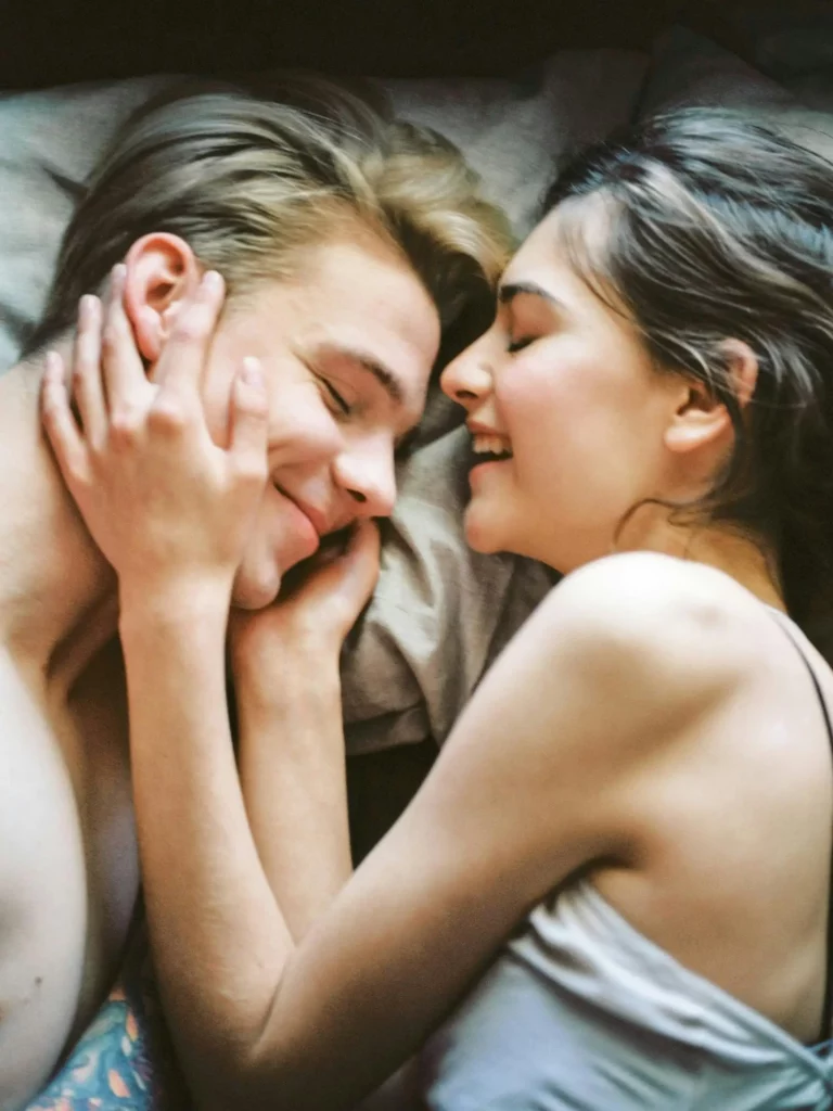 Couples lie on the bed and smiling at each other after an intense physical intimacy